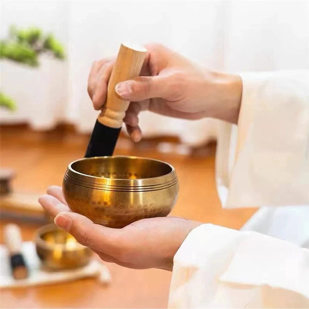Handmade antique singing bowl with wooden mallet on red cushion, set in a forest stream for meditation and spiritual clarity.
