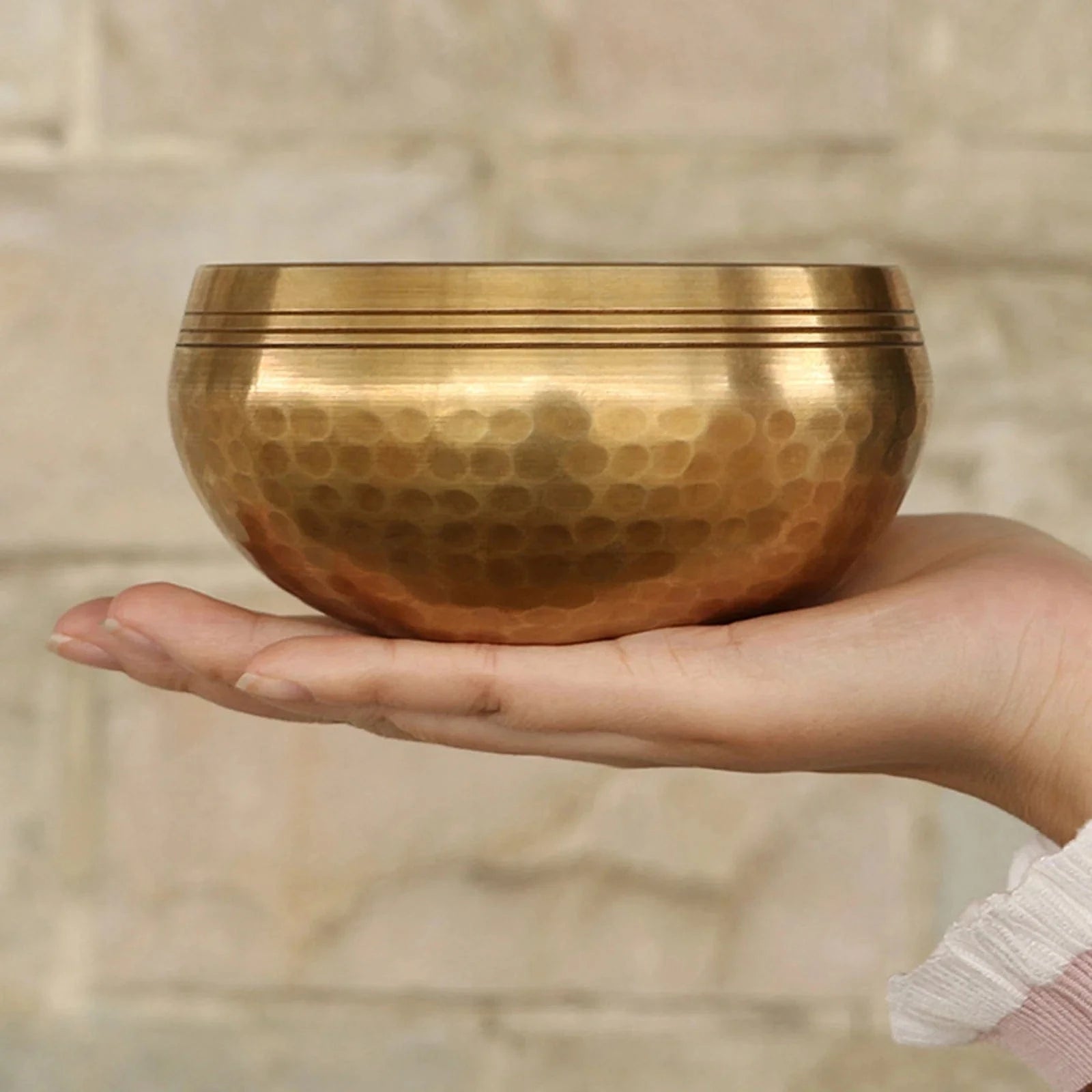 Handmade antique singing bowl with wooden mallet on red cushion, set in a forest stream for meditation and spiritual clarity.